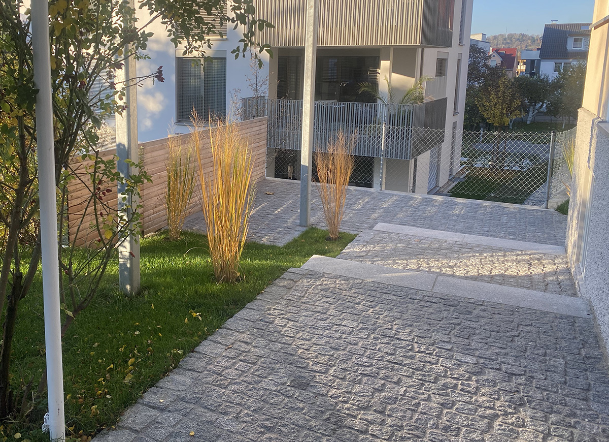 Paved driveway and landscaped entrance to a modern residential apartment building.