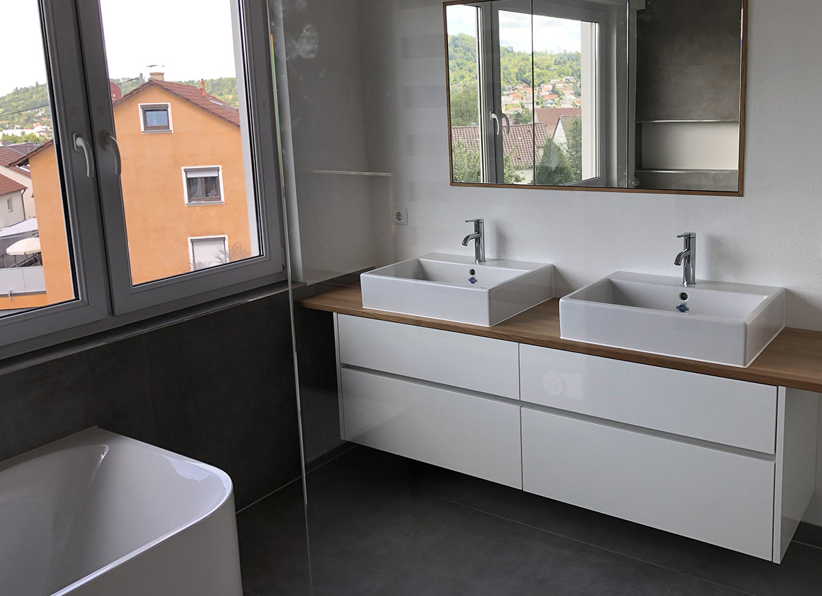 Modern bathroom with double vanity, freestanding bathtub, and large windows.