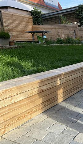 Raised wooden planter with green lawn in a landscaped garden.